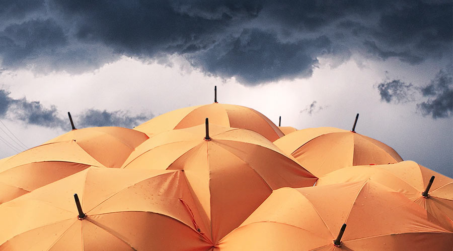 Des parapluies se regroupent pour former un bouclier face au temps très sombre et nuageux.