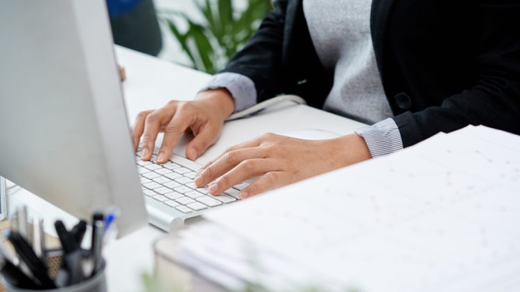 Photo de mains en train de taper sur les touches d'un clavier d'ordinateur