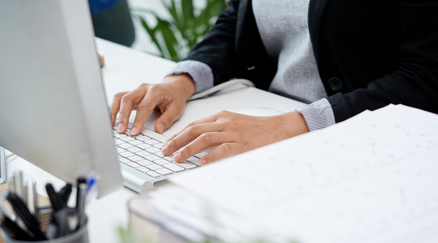 Photo de mains en train de taper sur les touches d'un clavier d'ordinateur