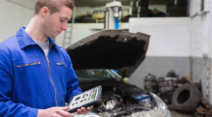 Auto mechanic checking on a tablet the repair tasks to perform on the vehicle